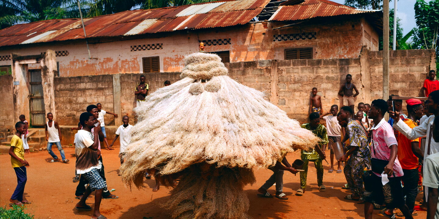 a zangeto spirit costumed in flowing raffia spins as people gather around